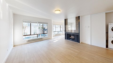 A spacious living room with a fireplace and a washing machine in the corner.