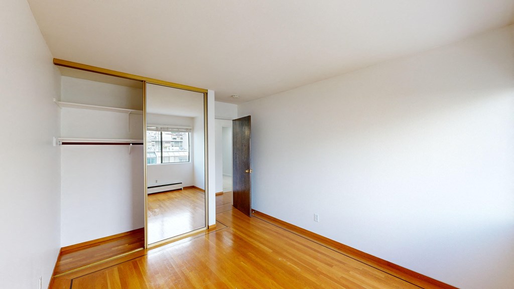 Bright bedroom with wood-like floor and a closet with mirror