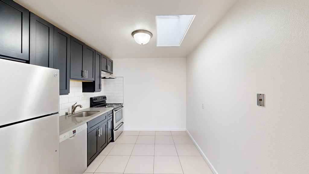 Kitchen with cabinets, refrigerator, stove, range hood, and sink