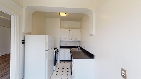 A kitchen with white appliances and a black countertop.