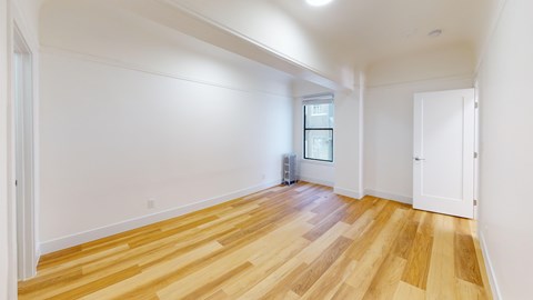 A room with wooden flooring and white walls.