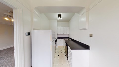A kitchen with white cabinets and a black countertop.