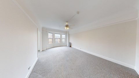 A room with a carpeted floor and a window with blinds.