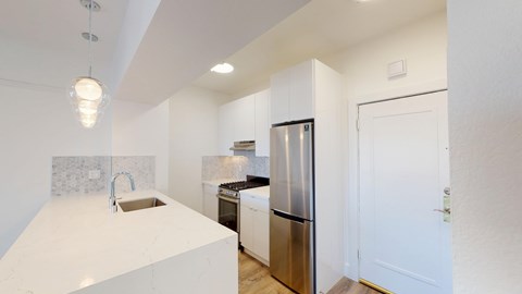 A modern kitchen with a stainless steel refrigerator and a white countertop.