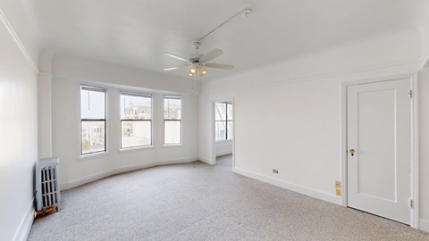 A spacious room with a ceiling fan and carpeted floor.