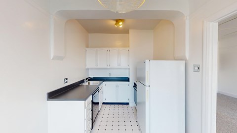 A kitchen with white cabinets and a black countertop.