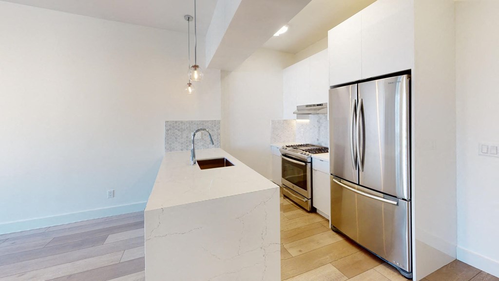 a white kitchen with stainless steel appliances and a large island