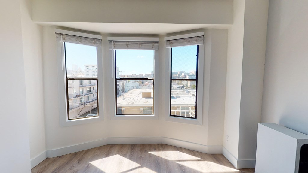 a living room with three windows and a wood floor