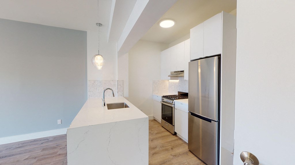 a white kitchen with stainless steel appliances and a large island