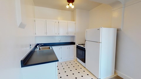 A kitchen with white cabinets and a black and white floor.