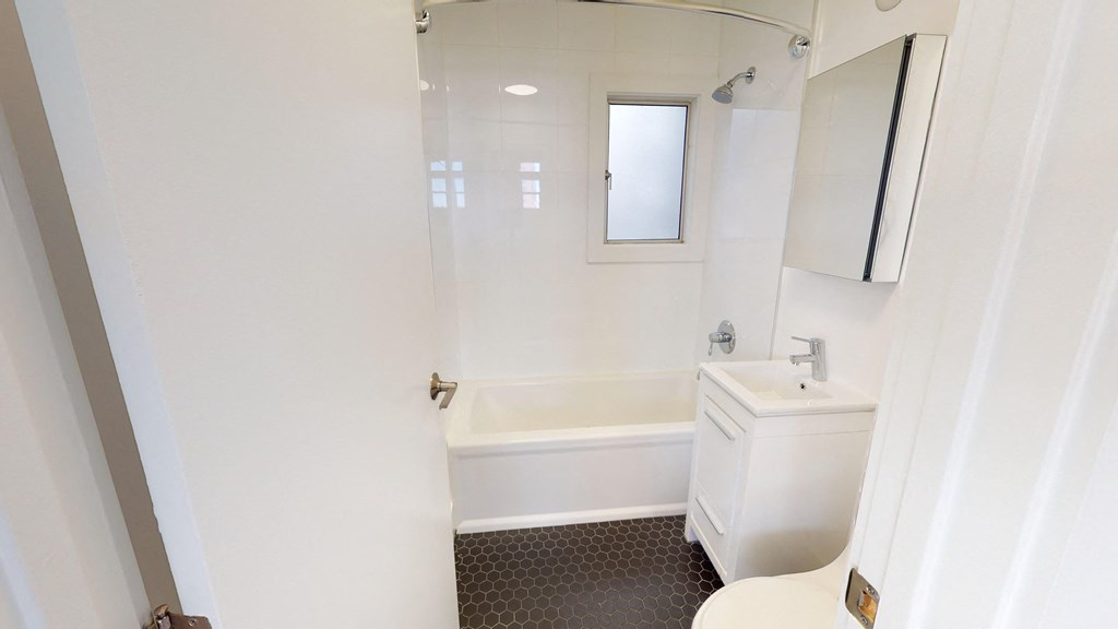 a white bathroom with a tub and a sink and a mirror