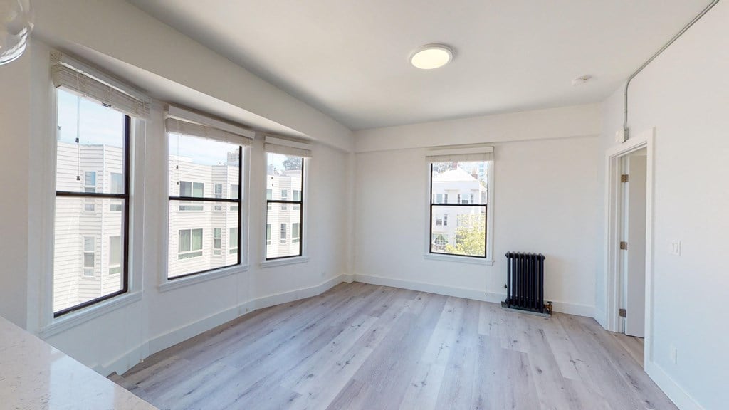 an empty living room with wood floors and large windows