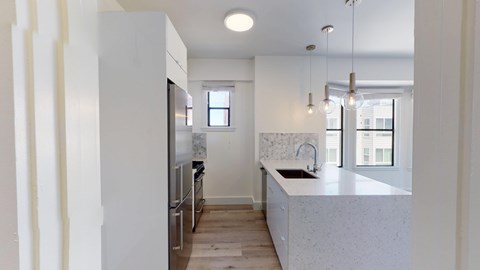 A kitchen with a white counter top and a window.