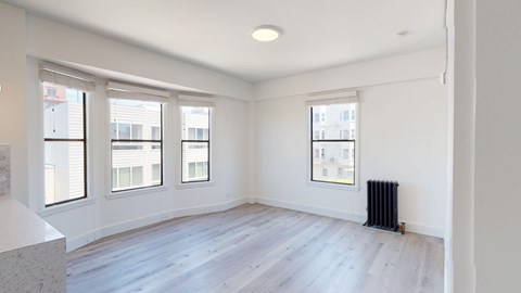 A room with a white wall and a window with a view of a building outside.