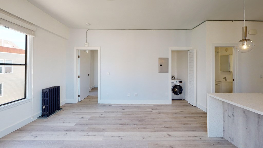 a living room with white walls and wood floors and a washing machine