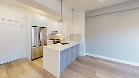 A kitchen with a white island and wooden floors.