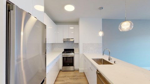 A modern kitchen with a stainless steel refrigerator and white cabinets.