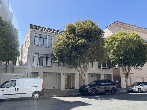 A white van is parked on the street in front of a building.