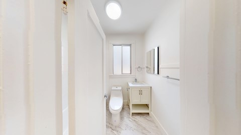 A white bathroom with a toilet, sink, and mirror.