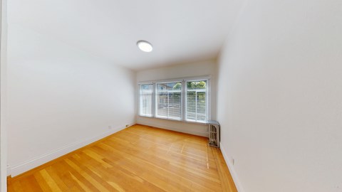 A room with wooden flooring and a window with blinds.