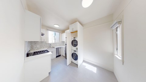 A white kitchen with a black stove top and a washing machine in the wall.