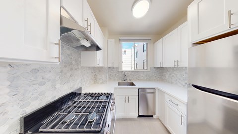 A modern kitchen with white cabinets and stainless steel appliances.