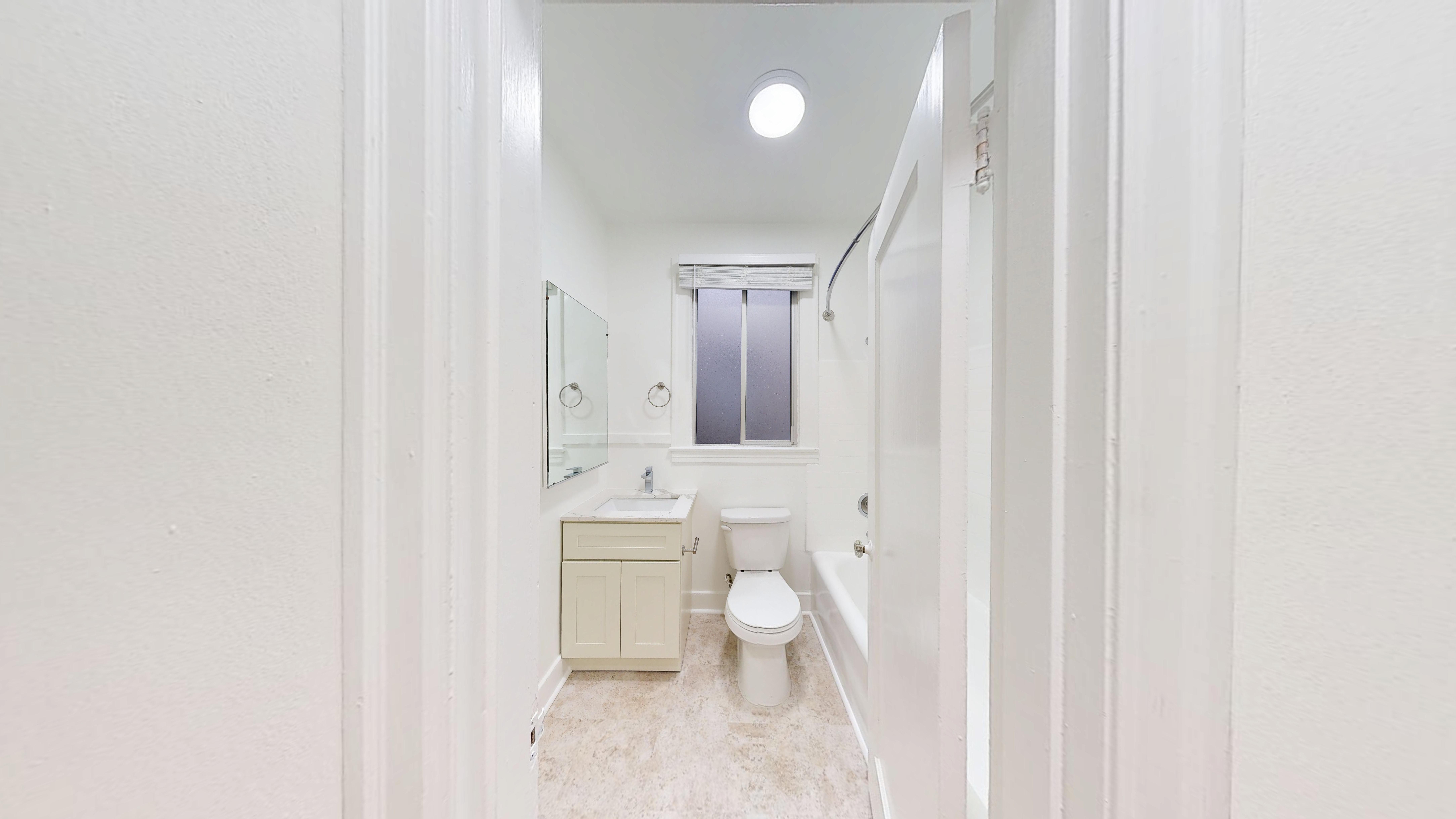 A white bathroom with a toilet, sink, and mirror.