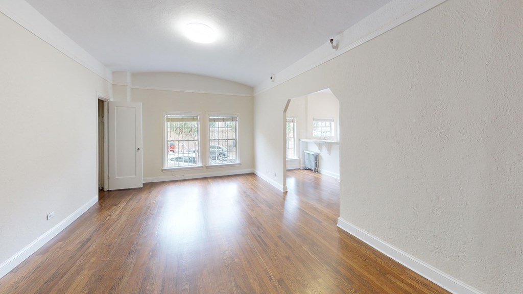 an empty living room with wood floors and white walls
