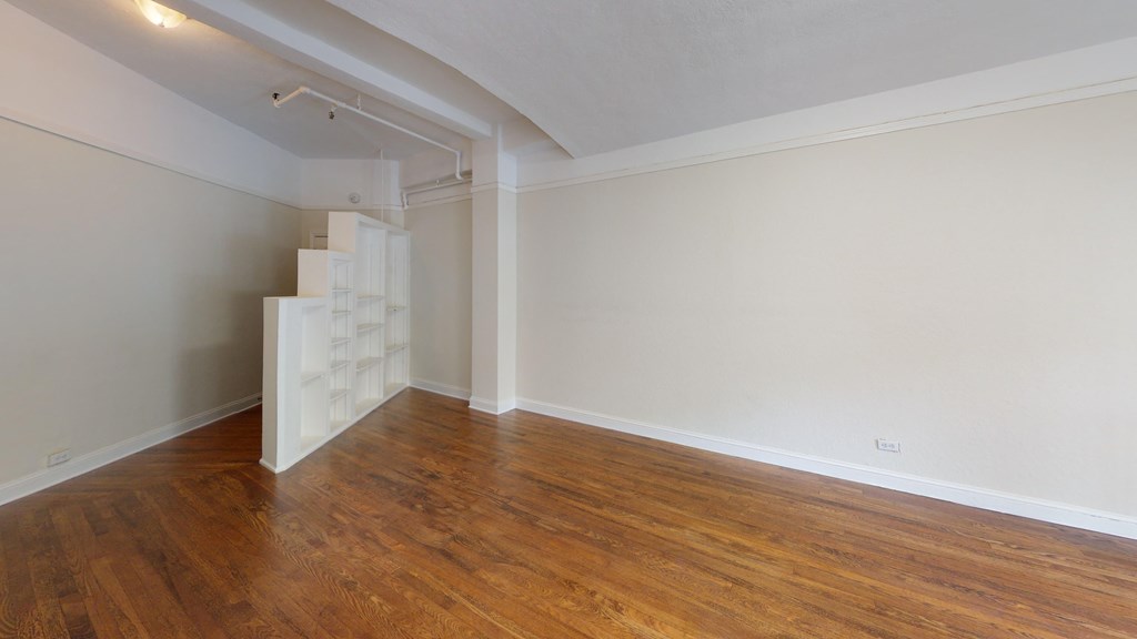an empty living room with wood floors and a staircase in the corner
