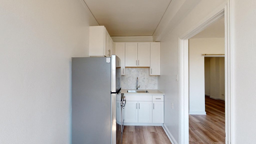a kitchen with white cabinets and a refrigerator