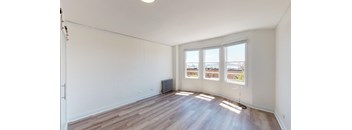 an empty living room with wood flooring and three windows