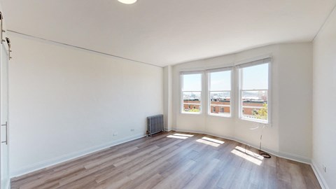 an empty living room with wood flooring and three windows