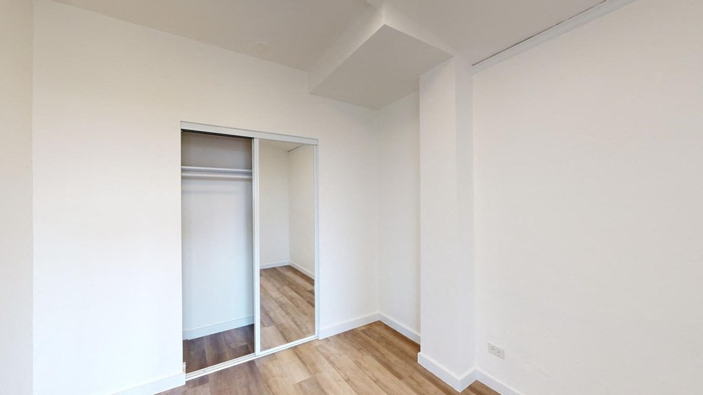 a sliding closet door in a room with wood floors and white walls