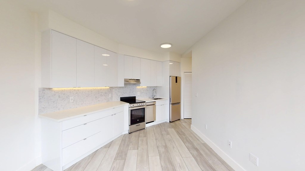 Kitchen featuring cabinets, stainless steel appliances, a marble backsplash, and wood flooring, bright and spacious design