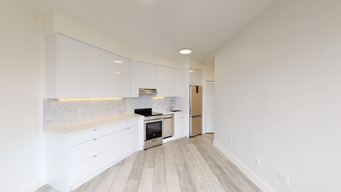 A kitchen with white cabinets and a wooden floor.