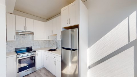 A modern kitchen with white cabinets and stainless steel appliances.