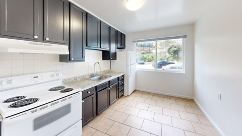 A kitchen with a white stove and black cabinets.