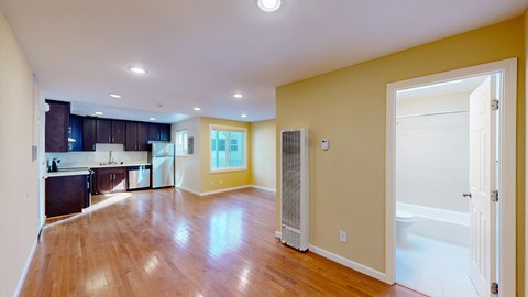 A spacious kitchen and living room with hardwood floors and a large window.