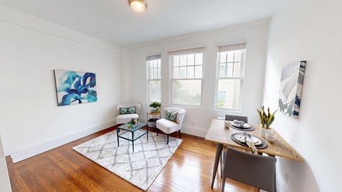 A dining room with a table set for two and a painting on the wall.