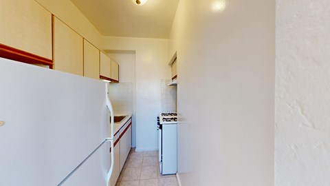 A white refrigerator is in a kitchen with white walls.