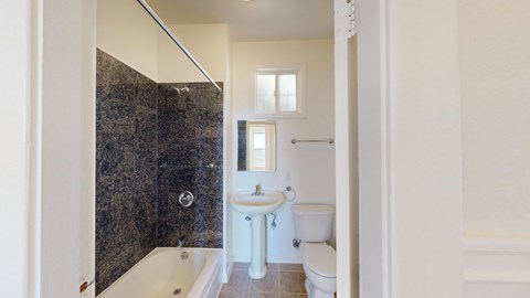 A bathroom with a white toilet, sink, and bathtub.