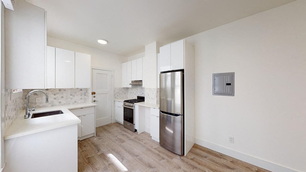 a kitchen with white cabinets and a stainless steel refrigerator