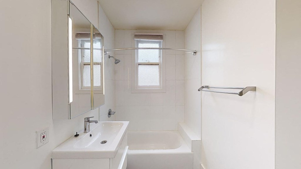 a white bathroom with a sink and a tub