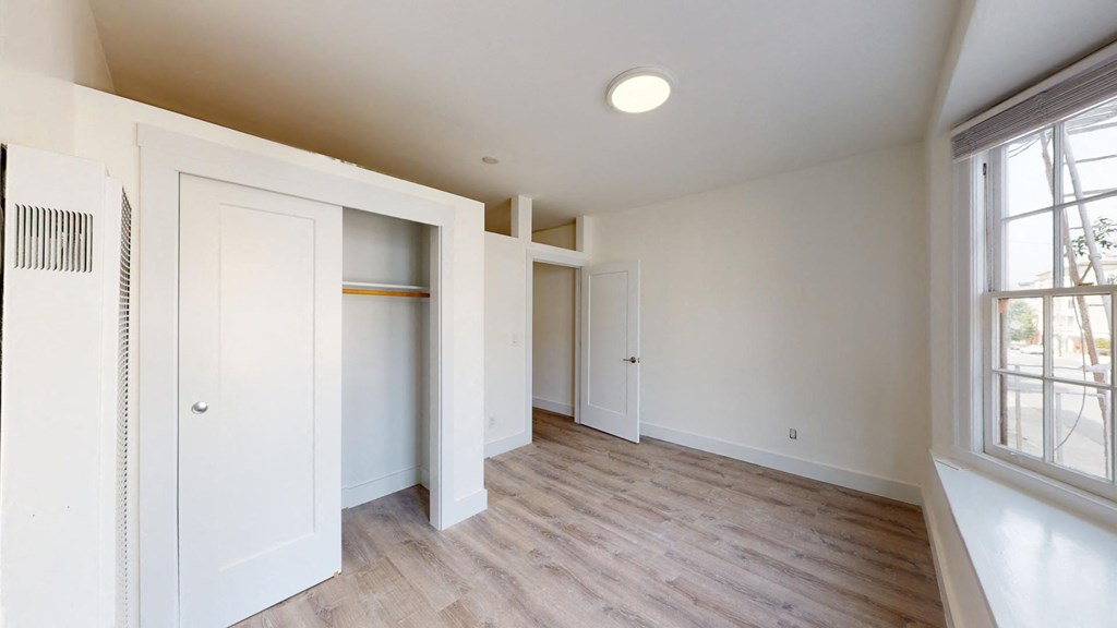 an empty room with white closets and a window