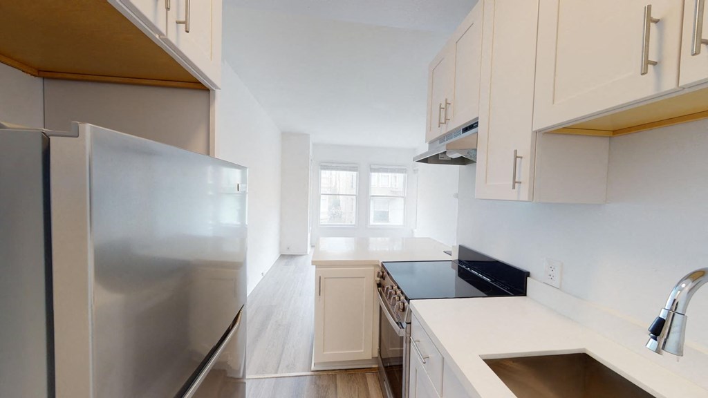 a kitchen with white cabinets and a stainless steel refrigerator