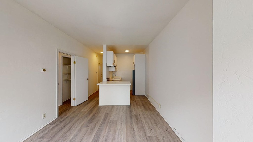 a renovated living room and kitchen with white walls and wood floors