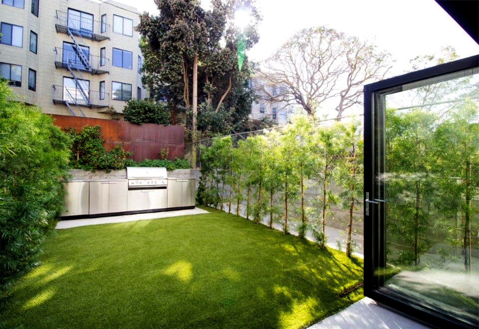 a backyard with a green lawn and a glass door