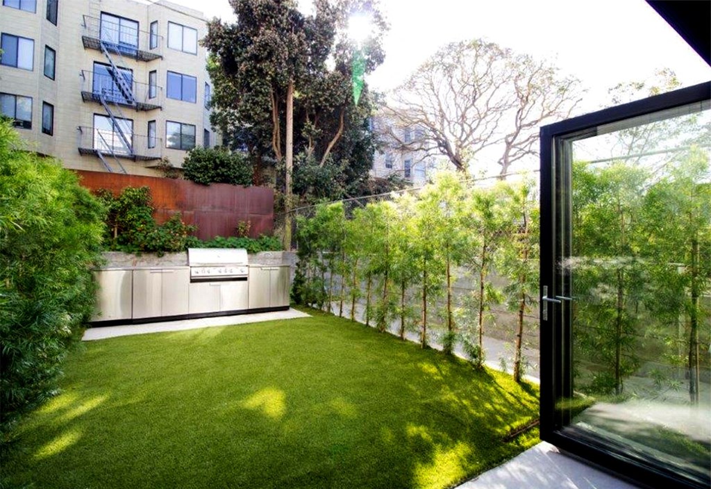 a backyard with a green lawn and a glass door