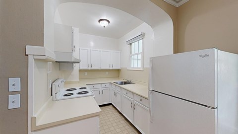 A white kitchen with a refrigerator on the right.