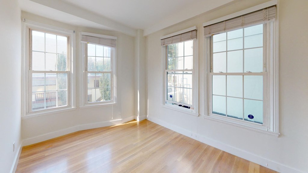 an empty living room with three windows and a wood floor